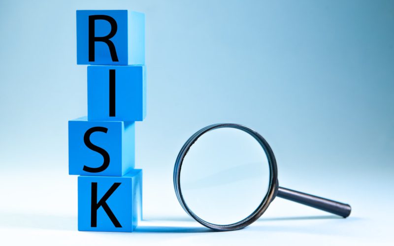 Blue blocks spelling risk next to a magnifying glass