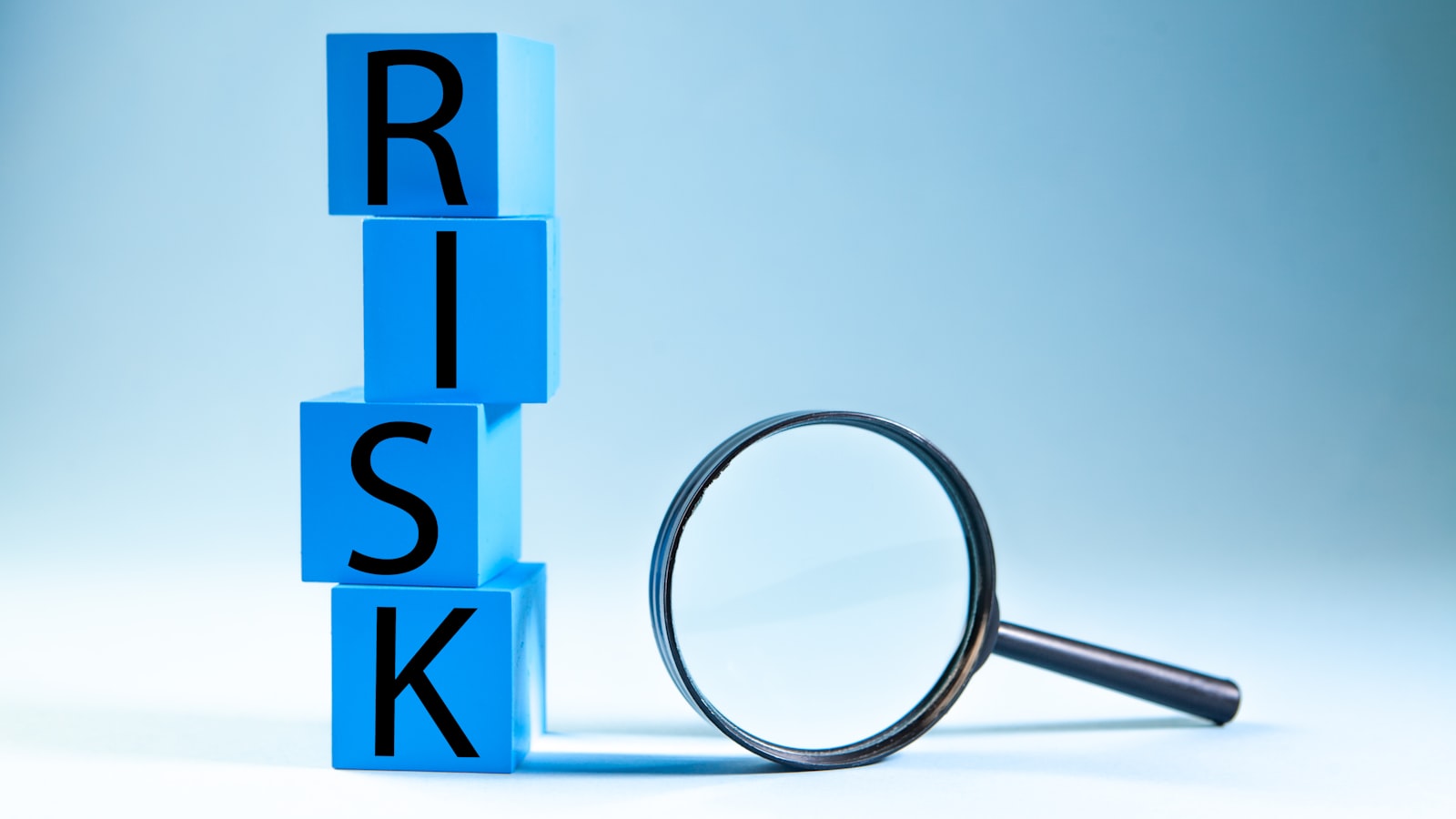 Blue blocks spelling risk next to a magnifying glass