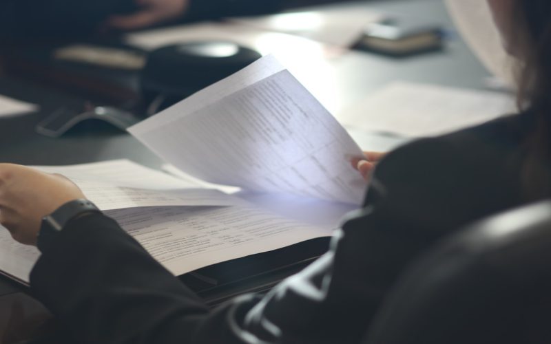a woman sitting at a table reading a paper