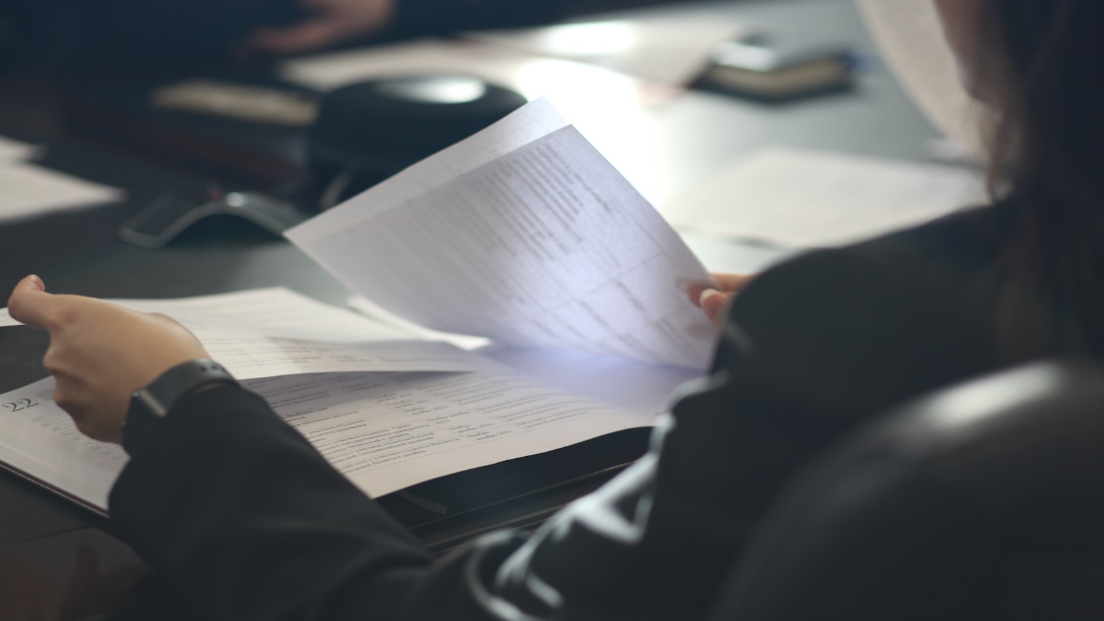 a woman sitting at a table reading a paper