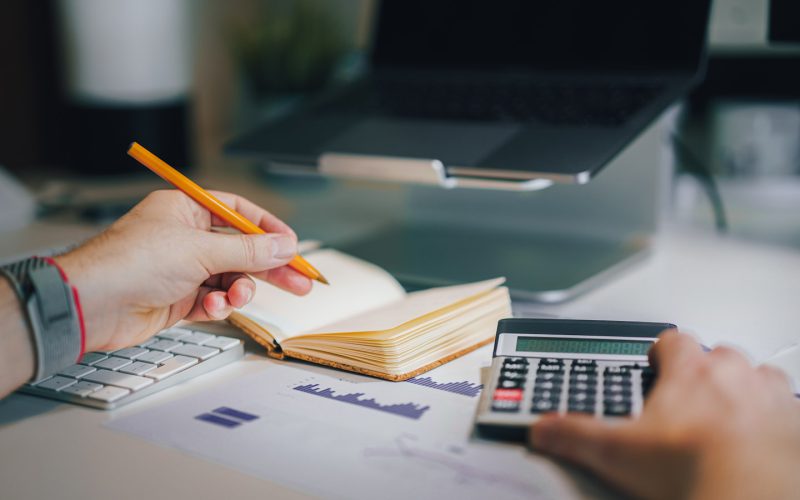a person sitting at a desk with a calculator and a notebook