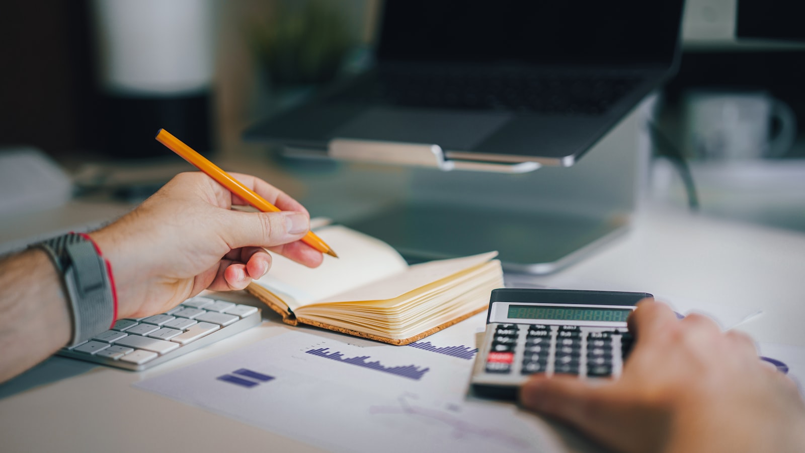 a person sitting at a desk with a calculator and a notebook