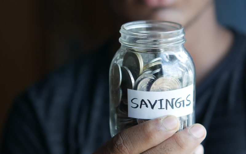 a man holding a jar with a savings label on it