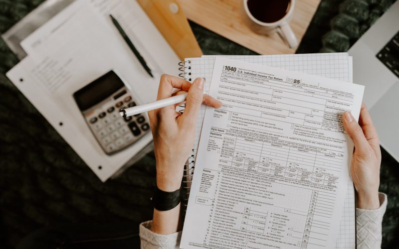 Person reviewing documents with calculator and laptop