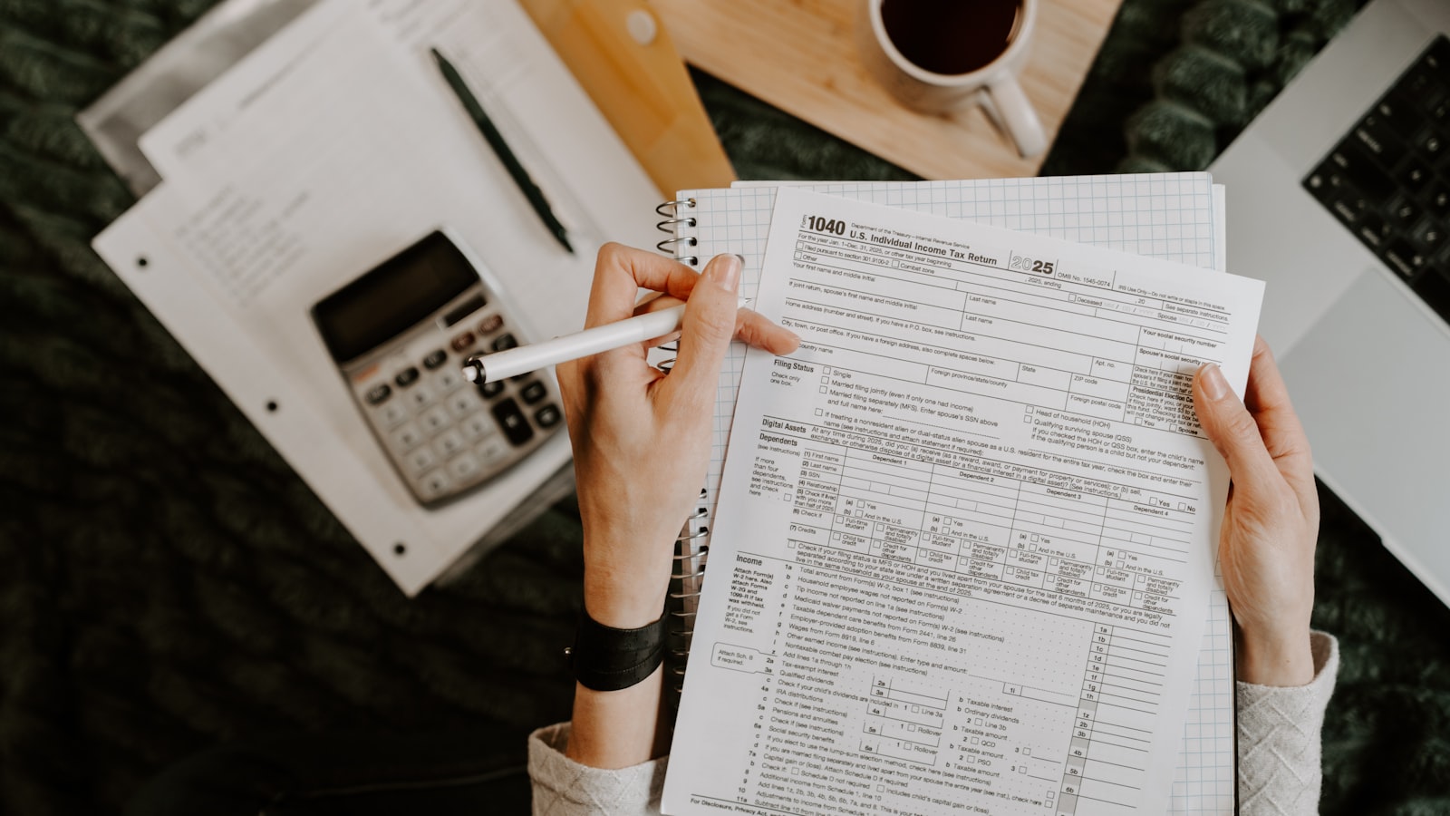 Person reviewing documents with calculator and laptop