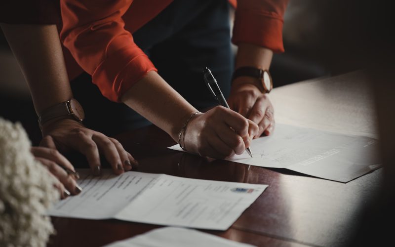 person in orange long sleeve shirt writing on white paper