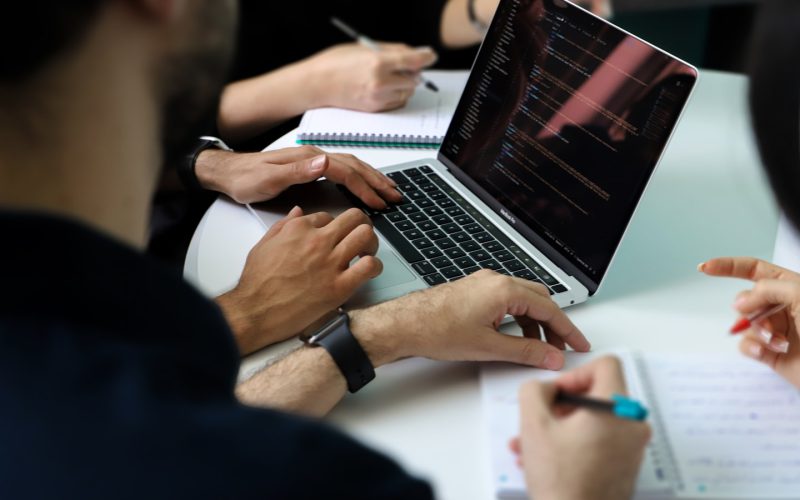a group of people sitting around a laptop computer