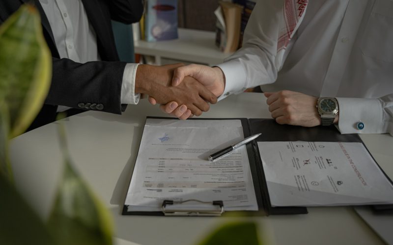 two people shaking hands over a piece of paper