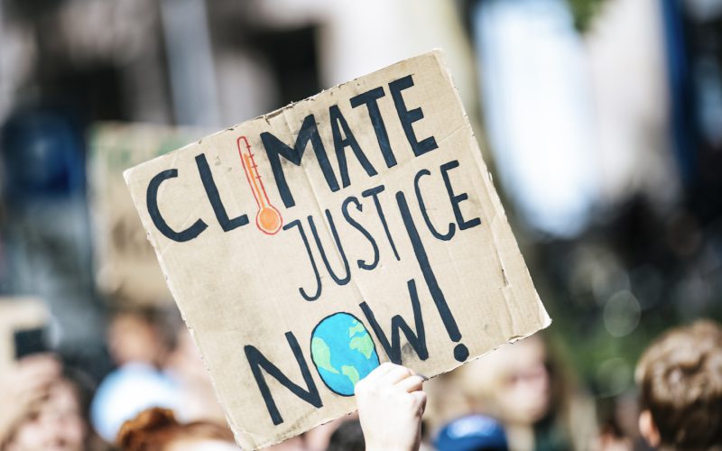 people gathered outside buildings holding Climate Justice Now signage