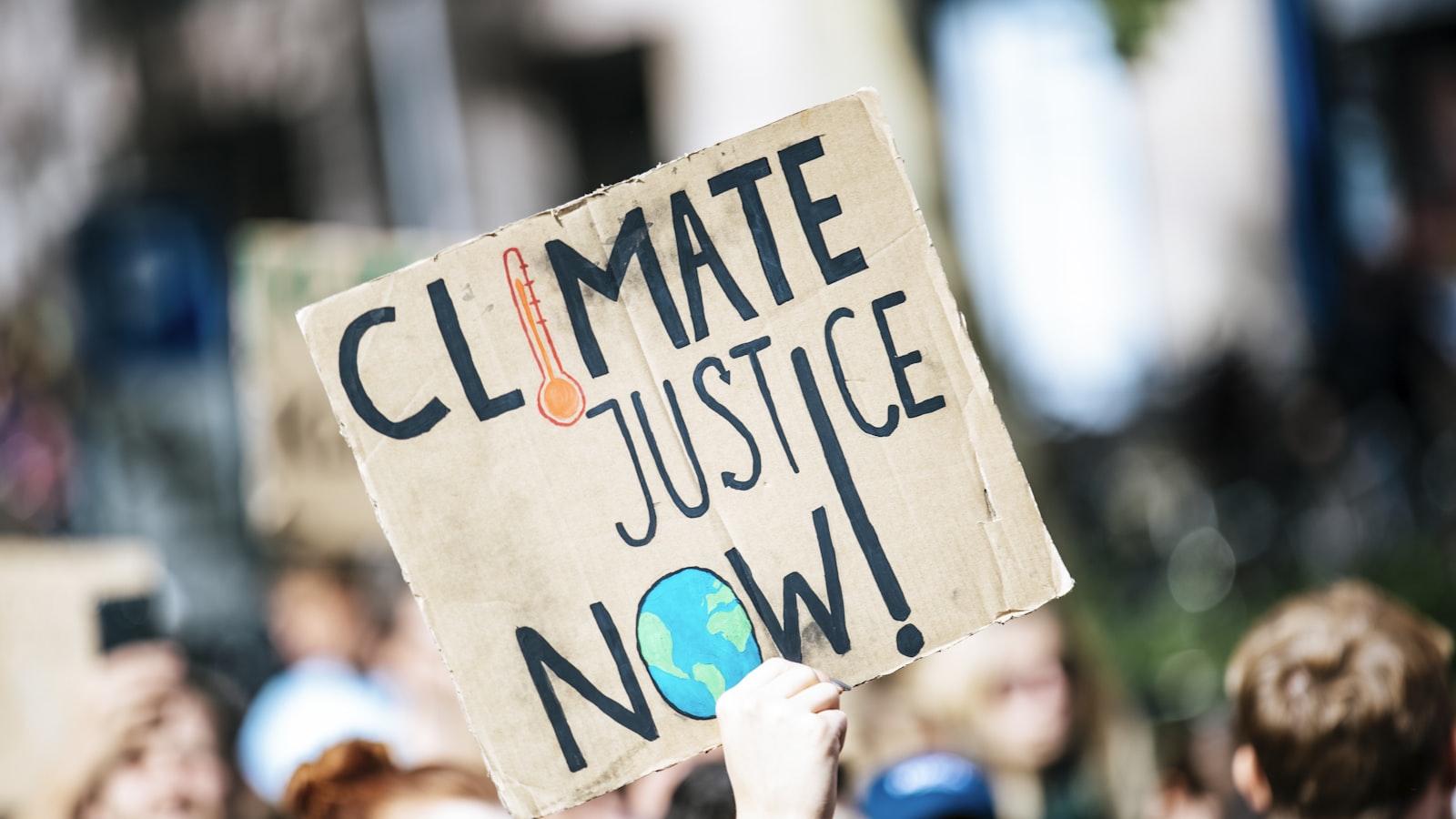 people gathered outside buildings holding Climate Justice Now signage