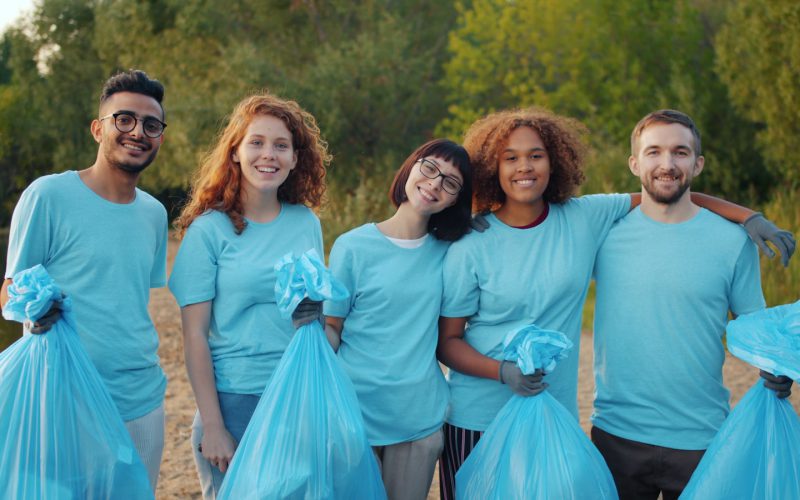 Diverse group of volunteers holding trash bags outdoors