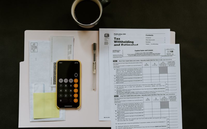 black Android smartphone near ballpoint pen, tax withholding certificate on top of white folder