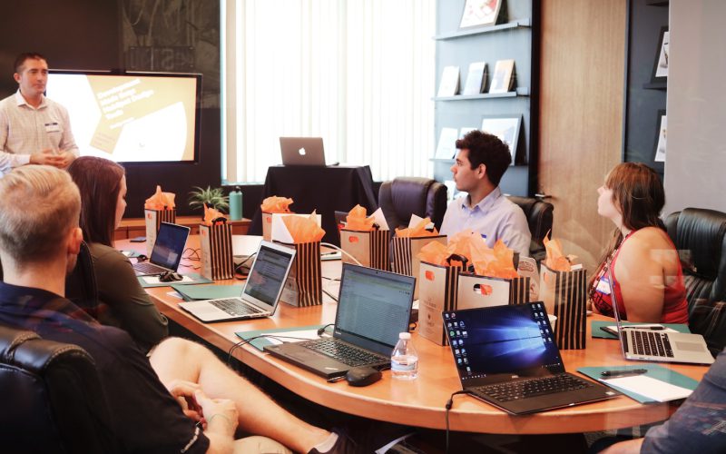 man standing in front of people sitting beside table with laptop computers