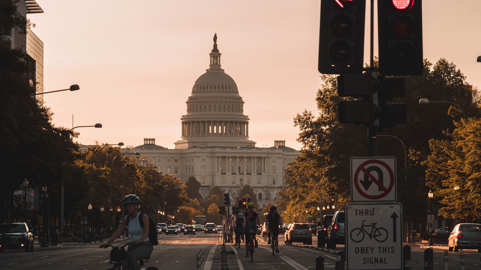 people biking on road and different vehicles viewing United States Capitol during daytime screenshot